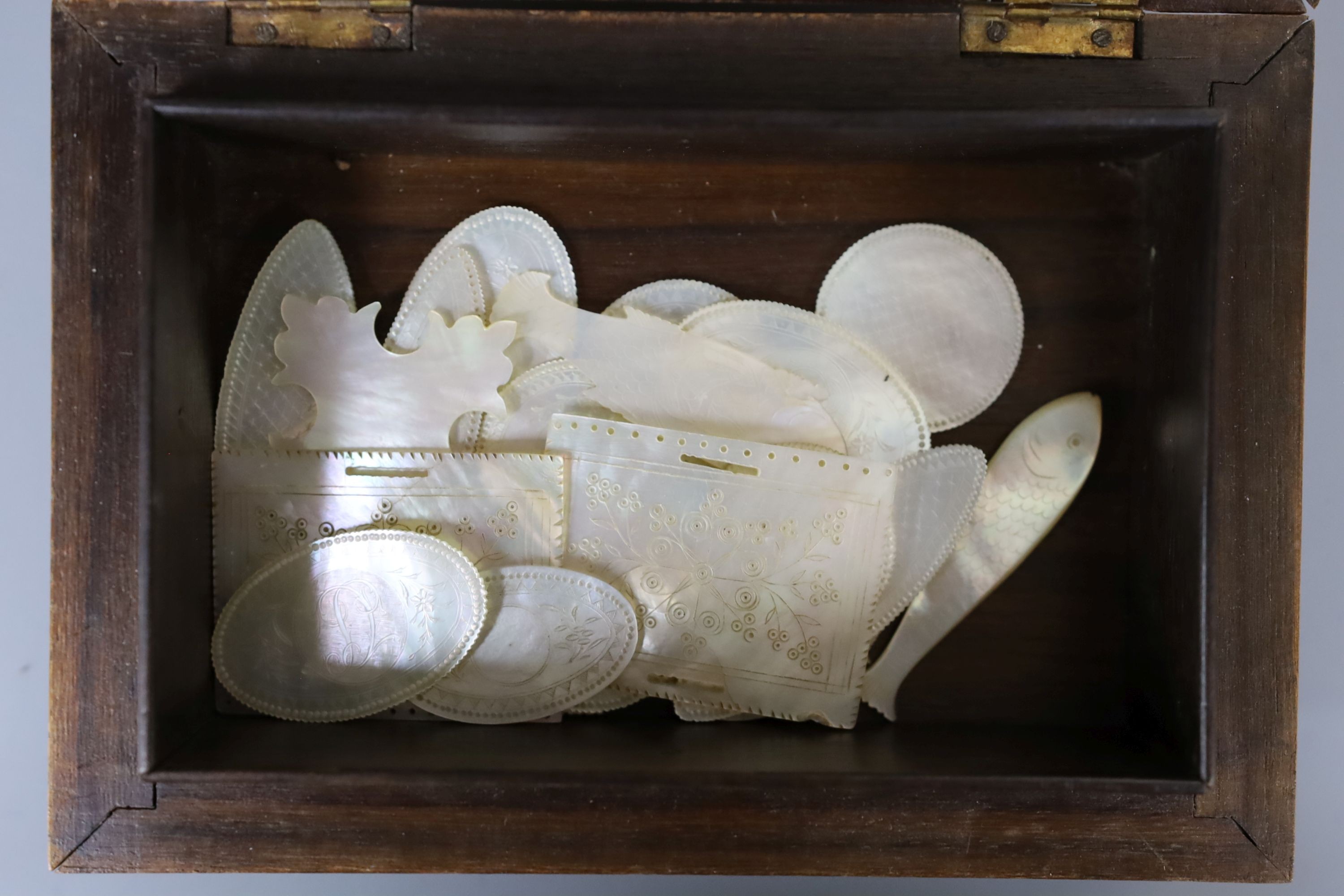 A 19th century bone and ivory draughts set, engraved mother of pearl gaming counters and stained bone tokens, all boxed